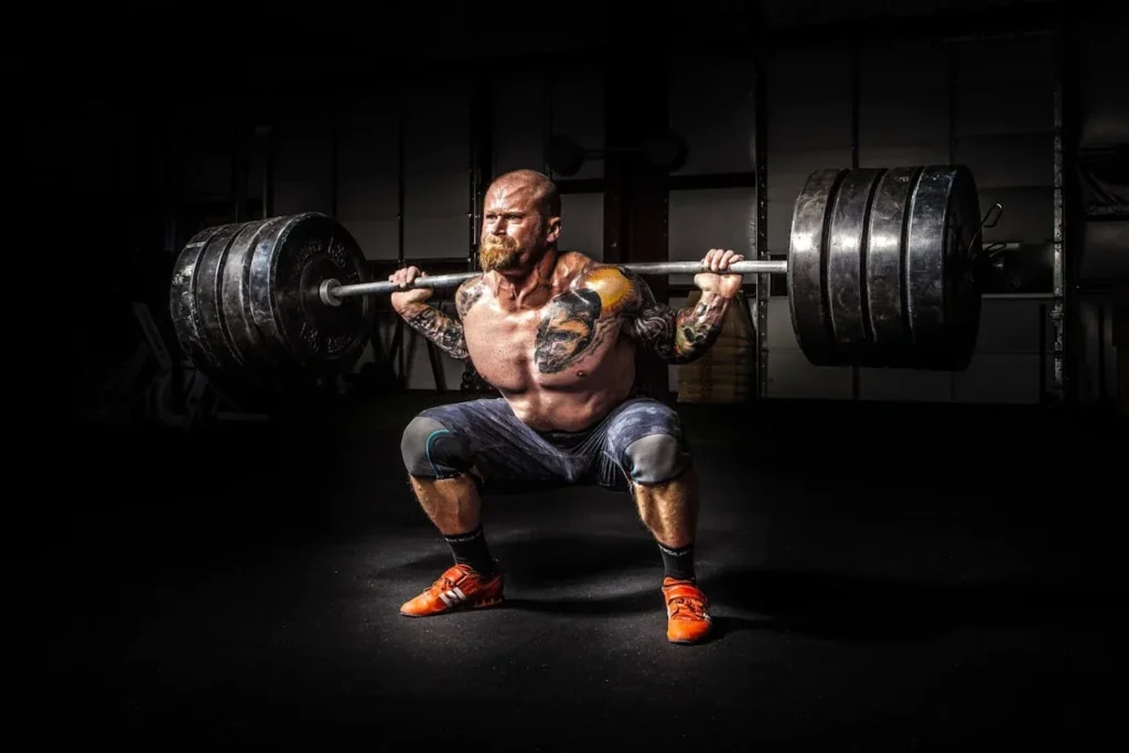 Strength Training and Functional Training: Unveiling the Differences 2 Strength training and functional training demonstrated by a man who is squatting a large amount of weight.