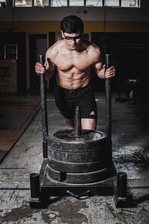 Strength Training and Functional Training: Unveiling the Differences 5 man pushing a weighted sled during functional training