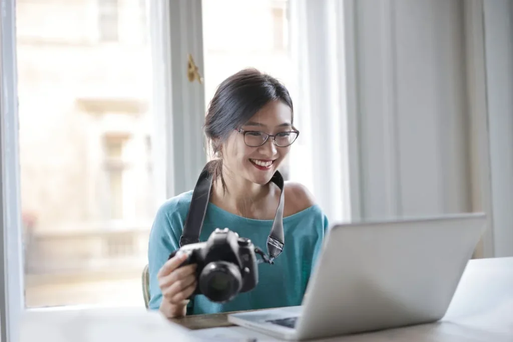 Discover 7 Powerful Exercise Benefits for Mental Health 5 woman smiling while working on her computer and holding a camera, as if downloading pictures