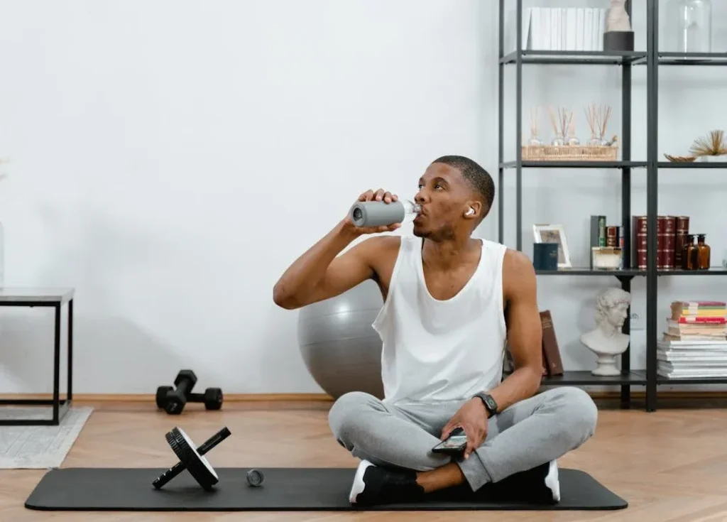 Starting Exercise at 40: 7 Essential Tips To Revolutionize Your Life 9 man sitting and drinking water sitting down at home on his exercise mat