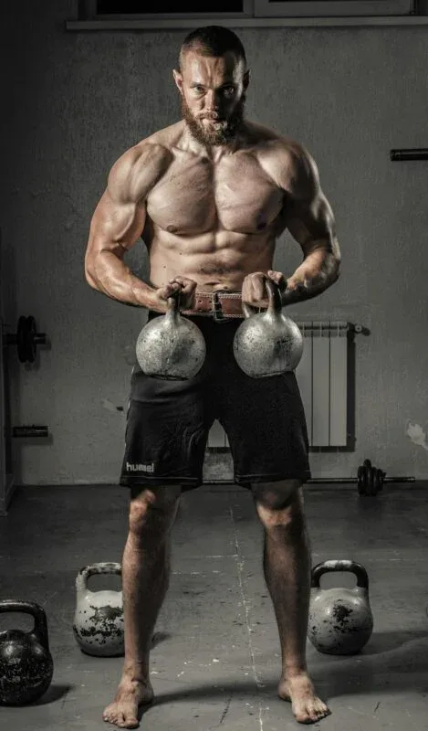 What is Strength: 6 Essential Elements 2 muscular man with kettlebells demonstrating what is strength