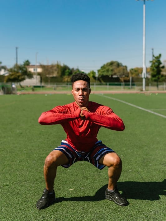 Functional Fitness for Everyday Life: 5 Essential Moves to Supercharge Your Health 3 man doing air squats in open athletic field