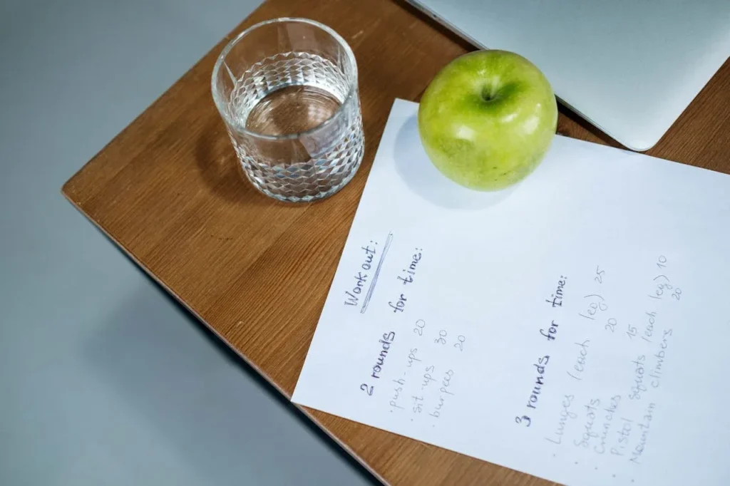 Minimalist Strength Training: 7 Proven Techniques for Great Results 8 workout plan on desk with water and apple