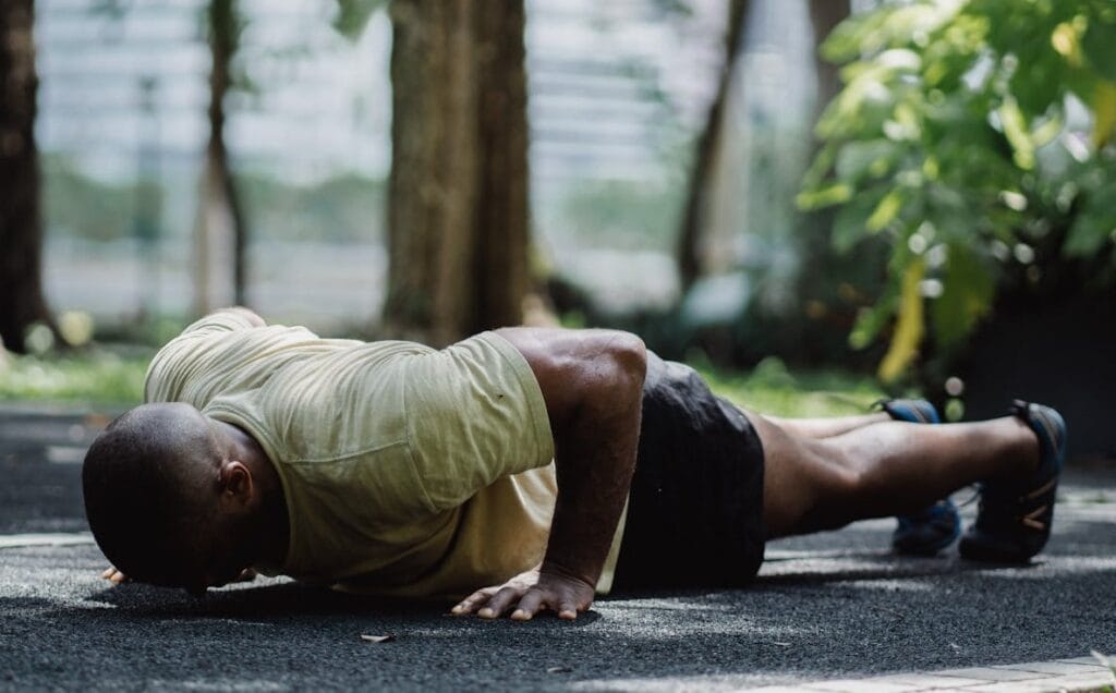 7 Proven Steps to Mastering 100 Push-ups in a Row 4 man in bottom position of pushups on a sidewalk in a park