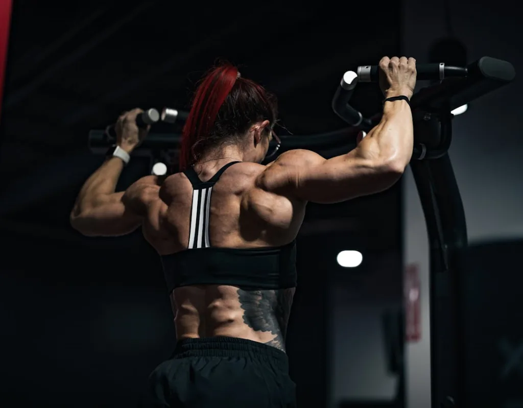 different pull ups image of woman with extreme back flex while doing pull ups in a darkened gym