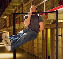man performing a one arm pull up at the top position