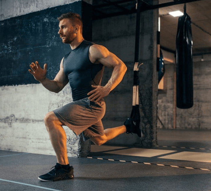 7 Powerful Leg Exercises Without Weights for Ultimate Strength 9 man using straps for Bulgarian split squats in a gym setting