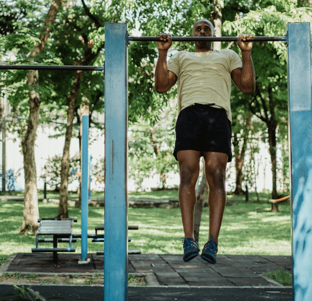 3 Powerful Calisthenics Exercises: Why Push-Ups, Pull-Ups, and Squats Are All You Need 4 man performing pull-ups in a park on a summer day