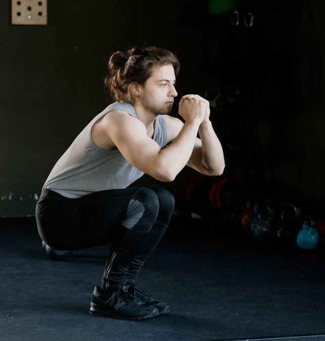 3 Powerful Calisthenics Exercises: Why Push-Ups, Pull-Ups, and Squats Are All You Need 5 man performing a deep squat in a darkened gym setting