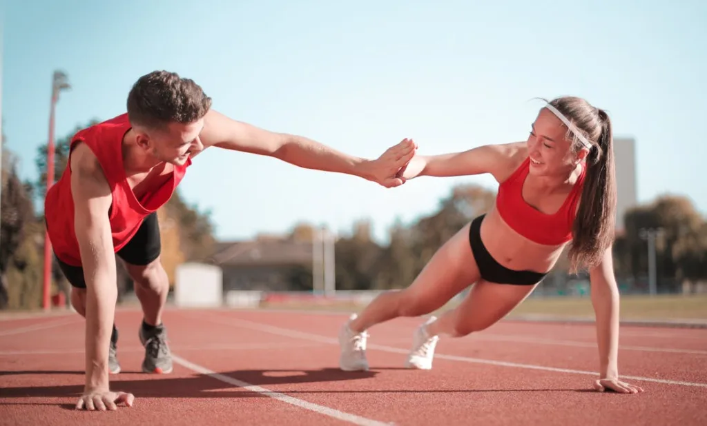 happy motivated couple giving each other a high five with one arm while other is in pushup position