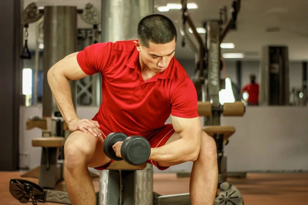 man doing single arm seated curls with a dumbbell