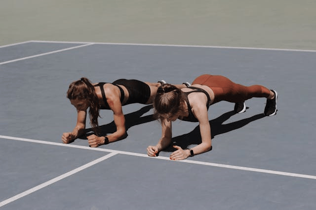 Calisthenics Plan for Beginners: 10 Incredible Steps to Get Started 5 two women demonstrating a plank hold on elbows outside