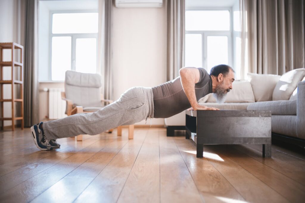 Unlock Strength and Longevity with These 5 Senior Fitness Workouts 5 image of a man working on senior fitness by using an intermediate progression of pushups on the coffee table
