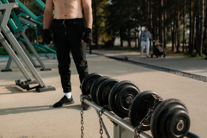Why Slow Metabolism and Weight Loss Get Harder as We Age: Unlock 3 Powerful Solutions for Lasting Results 4 image of man standing outside next to several sets of dumbbells.