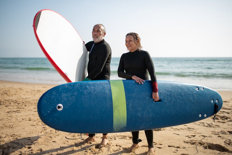 Why Slow Metabolism and Weight Loss Get Harder as We Age: Unlock 3 Powerful Solutions for Lasting Results 7 image of an older, very fit couple at the beach with surf boards.