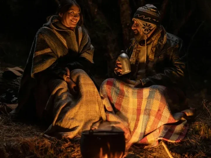 7 Surprising Health Benefits of Spending Time in Nature 6 a couple at night sitting at camp bundled up with blankets while smiling at each other