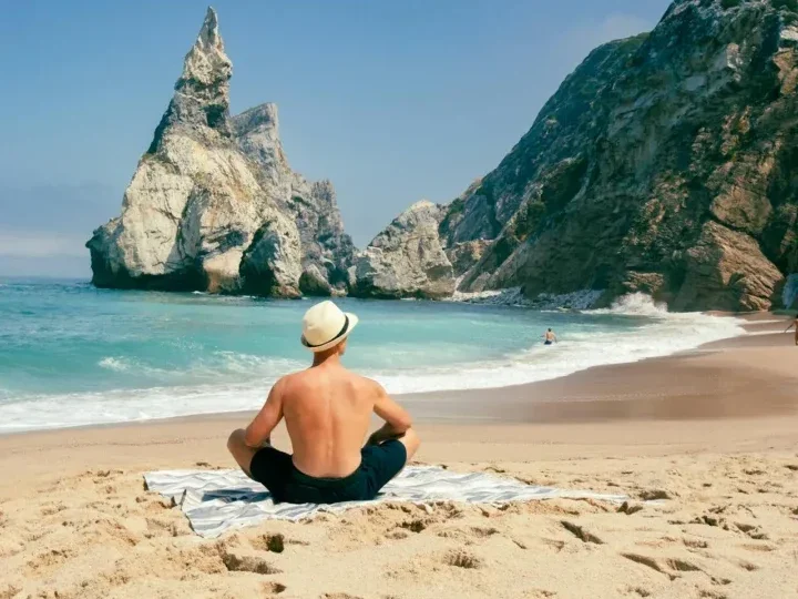 7 Surprising Health Benefits of Spending Time in Nature 8 image of a man sitting on the sand of a picturesque beach