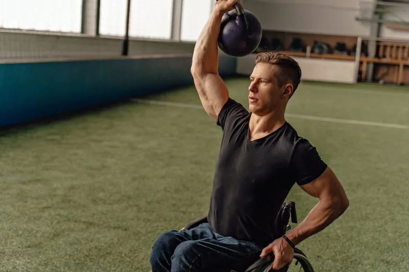 man in wheelchair performing a one-arm kettlebell press 