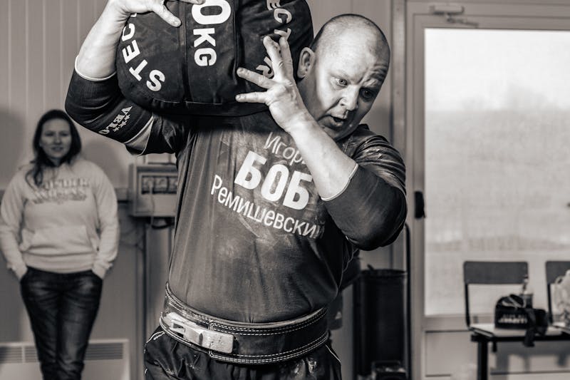 Farmer Strength: 7 Powerful Ways to Build Real-World Muscle 3 strongman hoisting a heavy sandbag on his shoulder