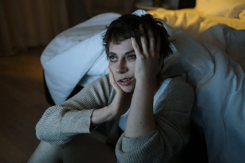 a woman demonstrates can lack of sleep make you gain weight by sitting next to her bed instead of sleeping