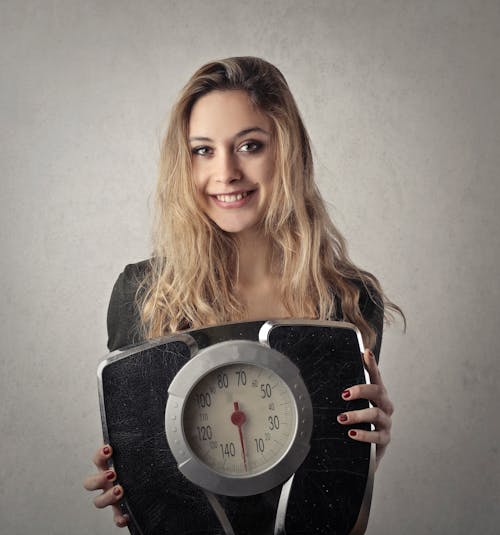 Why Is It So Hard to Lose Weight: Breaking Through the Challenges and Finding Solutions 2 woman holding a set of weight scales