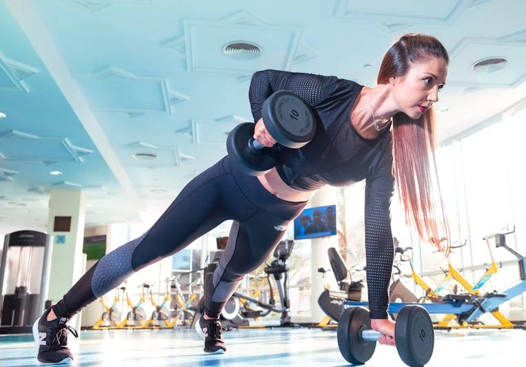 7 Powerful Functional Fitness Moves for Tough Times 6 woman in forward plank position performing a dumbbell row