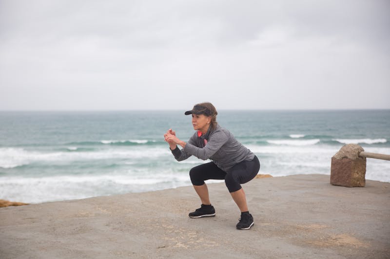 Stay Strong After 60: Bodyweight Strength Training for Seniors at Home 4 woman performing air squats beach side