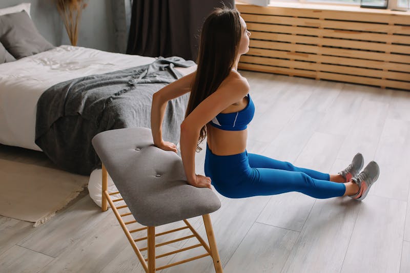 Strength Training Without Weights: 5 Powerful Minimalist Routines 2 woman doing chair dips in bedroom demonstrating strength training without weights